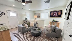 A living room with two grey sofas, a round coffee table, and a patterned rug. - Spacious 3BR Home - Fast Wifi - Parking - BBQ - Patio - Garden (Williston)