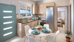 A modern kitchen with a dining area, featuring a view through a window, a built-in oven, and a refrigerator.