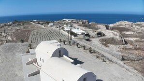 A white building with a curved roof, surrounded by a barren landscape and a clear blue sky.