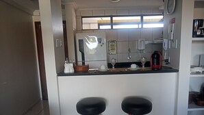 A modern kitchen with a central island, two stools, a coffee machine, and a refrigerator. - Cozy in Calhau near the coast  (Calhau São Luís)