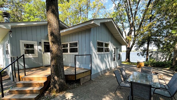 A house with a deck, a table and chairs, and a view of a lake. - Crow Wing Lakefront Cabin with Stunning Views, Perfect for All Seasons! (Fort Ripley)