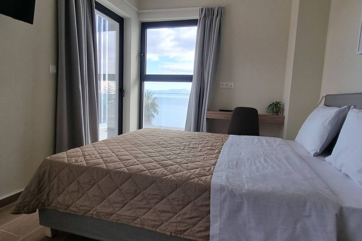Ein Hotelzimmer mit Bett, Schreibtisch und Meerblick.