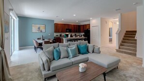 Una sala de estar moderna con un sofá modular, un comedor y una cocina.