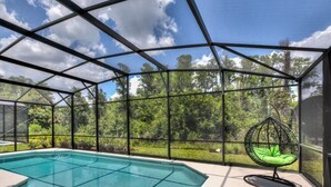 Una piscina cubierta con una hamaca colgante y vistas a un jardín exuberante.