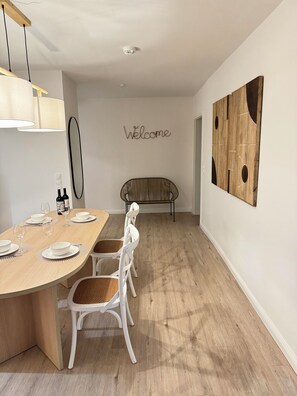 Ein Essbereich mit einem Holztisch, weißen Stühlen und einem 'Welcome'-Schild an der Wand.