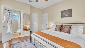 A bedroom with a bed, a ceiling fan, a painting, and a bathroom visible through an open door. - Close to Downtown, Close to Airport, Free Parking - Cozy Home in Austin, TX! (Austin)
