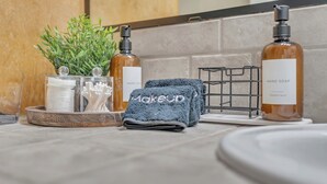 A bathroom vanity with a towel rack, a plant, and two bottles of hand soap. - Close to Downtown, Close to Airport, Free Parking - Cozy Home in Austin, TX! (Austin)
