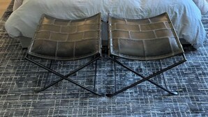 Una cama bien tendida con un cabecero gris, dos mesitas de noche con lámparas, un adorno de pared y una alfombra estampada.