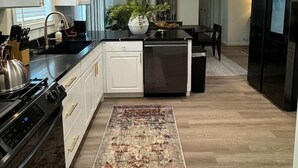Una cocina moderna con armarios blancos, un refrigerador negro y una isla central con pileta.
