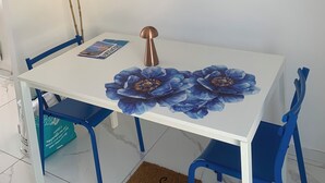 A white table with a floral table runner, two chairs, a decorative mirror, and two feather-like wall decorations. - Studio Bienvenue (Carry-le-Rouet)