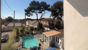 A residential area with a swimming pool, a covered patio, and a view of the surrounding neighborhood. - Studio Bienvenue (Carry-le-Rouet)