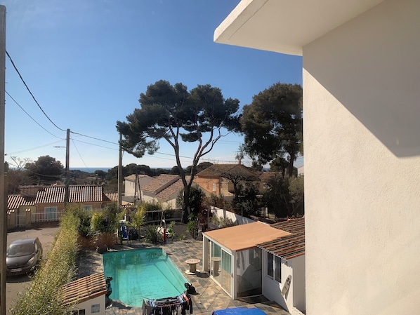 A residential area with a swimming pool, a covered patio, and a view of the surrounding neighborhood. - Studio Bienvenue (Carry-le-Rouet)
