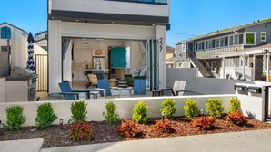 A modern two-story house with a patio area, a visible kitchen, and a staircase leading to an upper level. - Luxury Beachside Villa - Steps to the sand and beach (Huntington Beach)