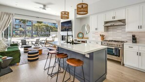 A modern kitchen with white cabinets, a large island, and a view of the outdoors. - Luxury Beachside Villa - Steps to the sand and beach (Huntington Beach)