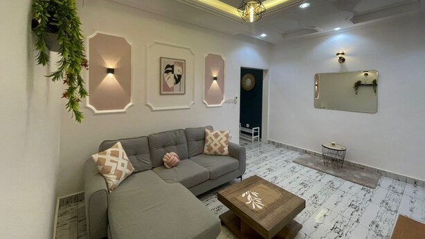 Una sala de estar moderna con un sofá modular gris, una mesa de centro de madera y apliques decorativos en la pared.