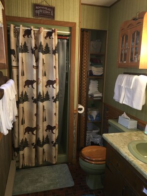 A bathroom with a shower curtain featuring animal prints, a toilet, a sink with a mirror, and a towel rack.