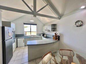 Una cocina moderna con una isla central, electrodomésticos integrados y un ventanal amplio.