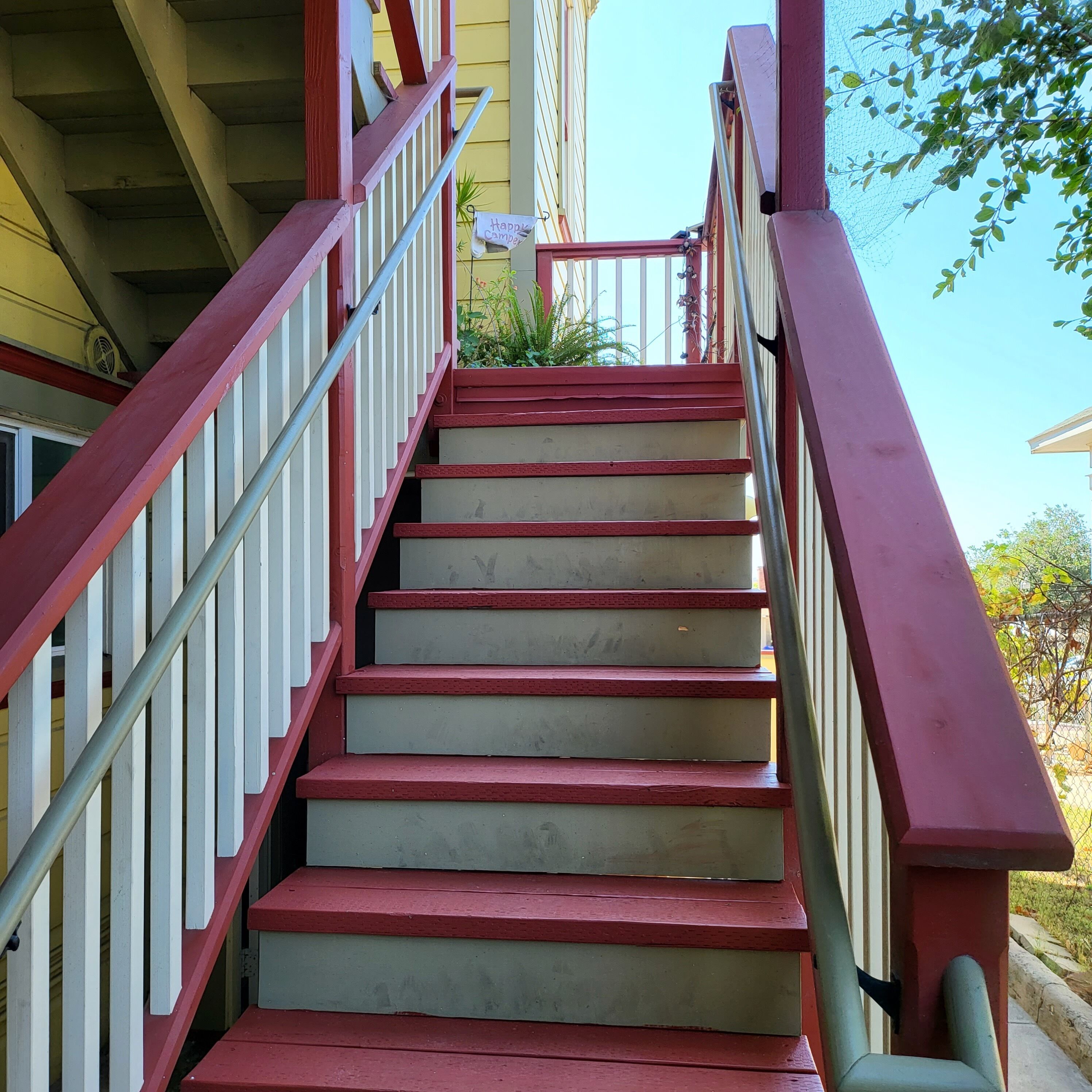 A set of outdoor stairs with red railings leading to a building entrance.