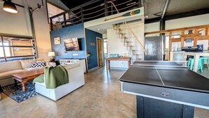 Amplia sala de estar con mesa de ping pong, sofá, mesa de centro y televisor.