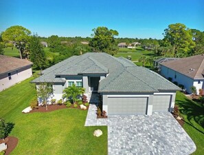 A two-story house with a grey roof, a garage, and a well-maintained lawn.