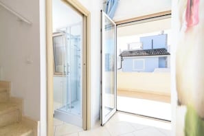 A bright room with a glass door leading to a balcony, a tiled floor, and a visible outdoor view. - Villa Martina (Fregene)