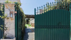 Une entrée fermée par un portail, avec un mur en pierre et un portail en métal.