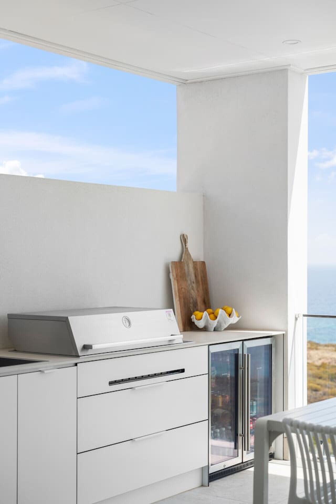 Una cucina moderna con piano cottura integrato, mobili bianchi e vista mare attraverso un'ampia finestra.