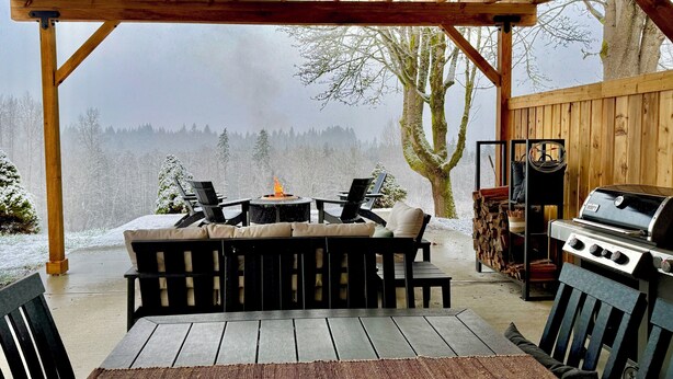 An outdoor patio with a wooden pergola, a grill, and a fire pit. - NEW Secluded Hillside Retreat on 10 acres with Stunning Views (Port Angeles)
