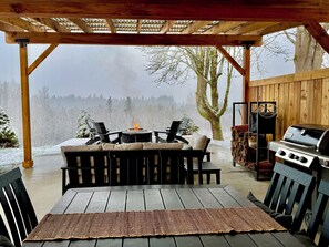 An outdoor patio with a wooden pergola, a grill, and a fire pit. - NEW Secluded Hillside Retreat on 10 acres with Stunning Views (Port Angeles)