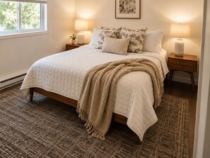 A bedroom with a bed, two bedside tables, a window, and a wall-mounted picture. - Downtown 2BR - Fast WiFi-Easy Parking -Self Check-in (Williston)