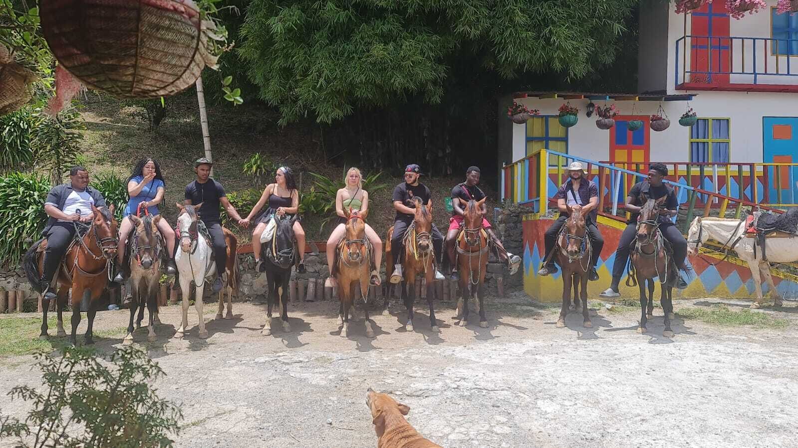 A group of people on horseback in an outdoor setting with a colorful building in the background.