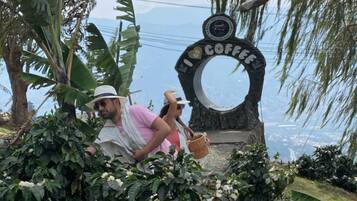 A sign with a coffee theme, surrounded by lush greenery and white flowers.