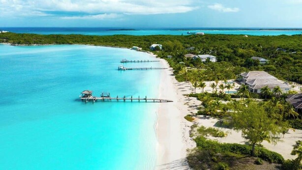 A tropical beach resort with clear turquoise waters, a wooden pier, and lush greenery. - NEW BluWakes #2 5BR Beachfront Villa/Pool/Luxury (George Town)