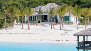 A beachfront property with a pool, palm trees, and a house with a thatched roof. - NEW BluWakes #2 5BR Beachfront Villa/Pool/Luxury (George Town)