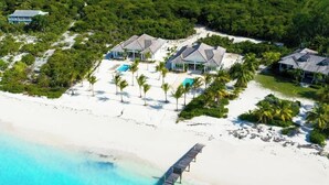 An aerial view of a beachfront resort with multiple villas, a swimming pool, and a pier. - NEW BluWakes #2 5BR Beachfront Villa/Pool/Luxury (George Town)