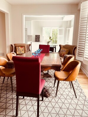 A dining area with a wooden table, six chairs, and a red rug. - Woodspring Vacation Home (Newmarket)