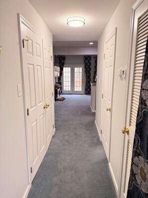 A hallway with white doors, a carpeted floor, and a ceiling light. - Family-friendly, Quiet, and Gated 3-bedroom Townhouse in Central Richmond (Richmond)