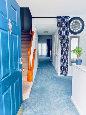 A hallway with a blue carpet, a staircase, and a door with a brass doorknob. - Family-friendly, Quiet, and Gated 3-bedroom Townhouse in Central Richmond (Richmond)