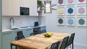 Una cocina moderna con microondas integrado, un lavamanos y una zona de comedor con mesa y sillas de madera.
