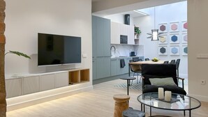 Una sala de estar moderna con televisor de pantalla plana, una mesa de centro de vidrio y un comedor con mesa y sillas.