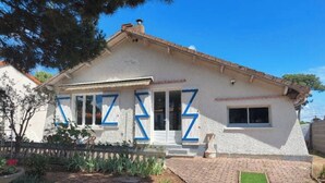 Una casa con fachada blanca, marcos de ventana azules y techo de tejas.