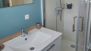 Un baño con lavamanos blanco, espejo y cabina de ducha de vidrio.