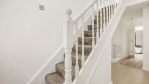 A staircase with white balusters and a carpeted landing. - Beautiful House in North London with Parking (London)
