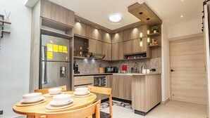 Een moderne keuken met houten kastjes, een inbouwoven en een eethoek met een ronde tafel en stoelen.