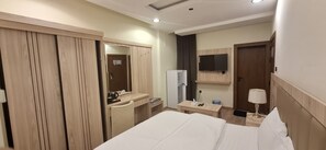 Ein Hotelzimmer mit Bett, Schreibtisch, Spiegel, Fernseher und Kleiderschrank.