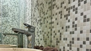 Ein Badezimmer mit einem großen Becken aus Stein, einer Duschkabine aus Glas und einer Wand mit Schachbrettmuster.