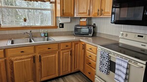 A kitchen with wooden cabinets, a stainless steel sink, a microwave, and an oven.