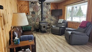A cozy living room with a stone wall, a fireplace, a comfortable leather sofa, and a television.