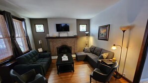 Una sala de estar con chimenea, un sofá, una mesa de centro y un televisor.