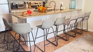 A kitchen with a central island, four bar stools, a microwave, a toaster, and a sink. - Discounted GroundFloor. King Bed. Queen Bunks.Twin bunks. Wheelchair Accessible. (Orange Beach)